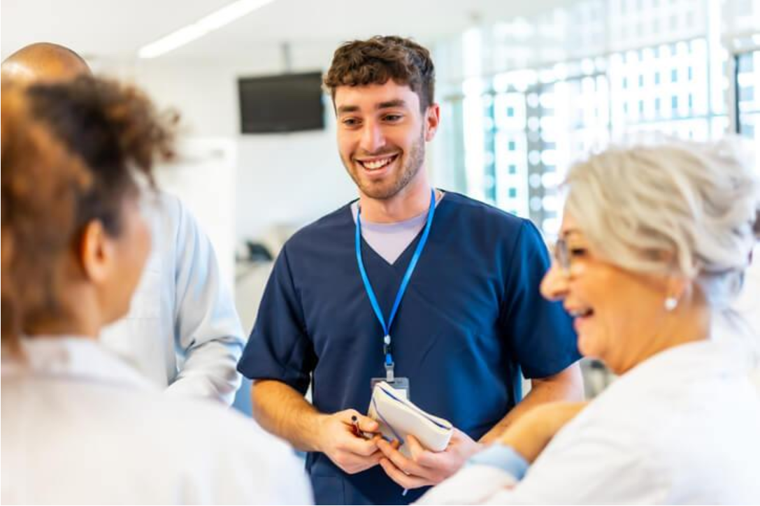 Continuing Care Assistant communicating with a client, family member, and healthcare team in a clinical setting.