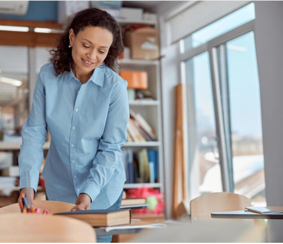 Early childhood educator organizing books and learning materials in a bright classroom before children arrive.