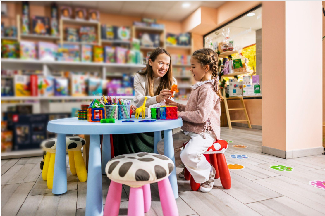 Early childhood educator helping a child explore colourful building toys during a hands-on learning activity.