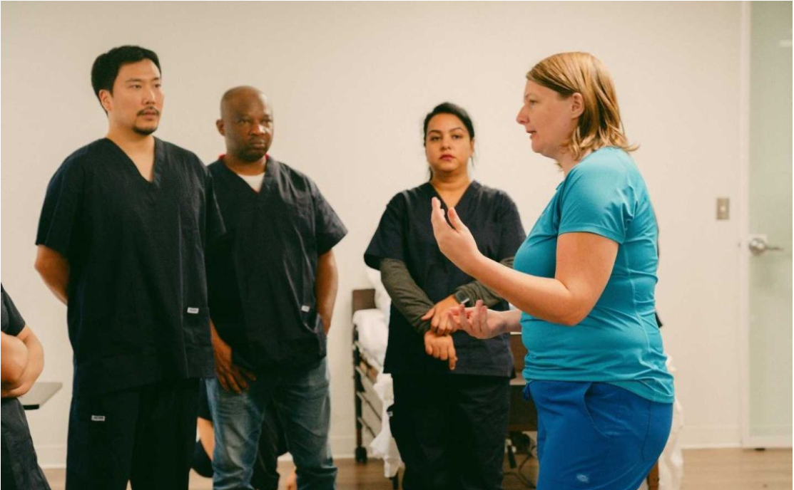 Healthcare instructor teaching a diverse group of Continuing Care Assistant students during a practical classroom session.
