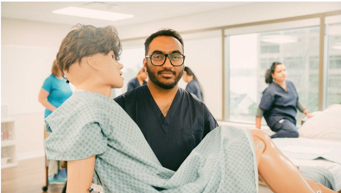 Continuing Care Assistant student practising patient positioning and bedside care using a healthcare training mannequin.