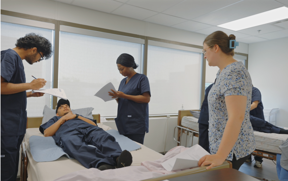 Continuing Care Assistant students practising patient assessment and care procedures in a simulated healthcare setting.