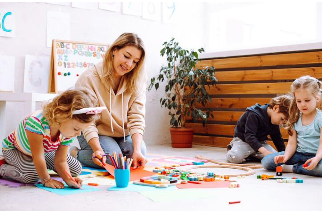 Early childhood educator guiding children through art, building, and play-based activities in a bright classroom.