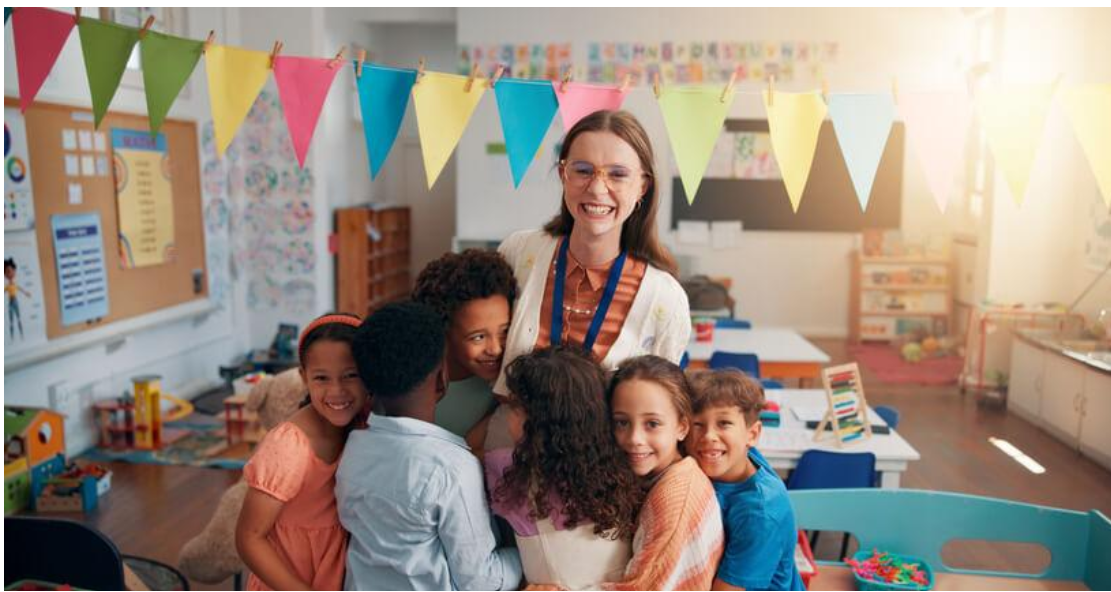 Smiling early childhood educator surrounded by a diverse group of children in a colourful childcare classroom.