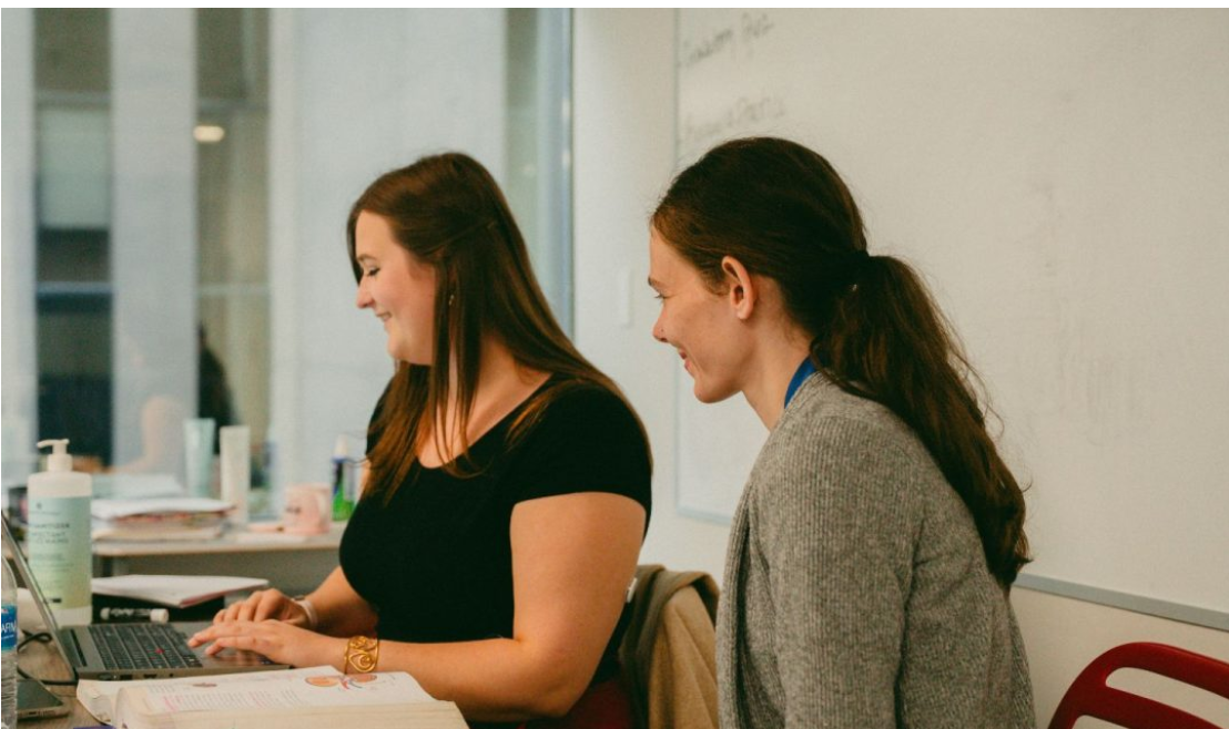 Two adult students working together on a laptop during an Early Childhood Education class.