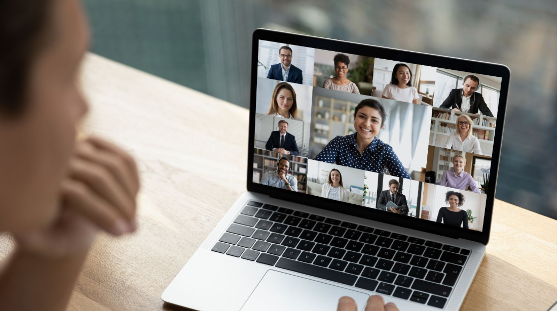 Student participating in an online class with a diverse group of learners through a laptop video call.