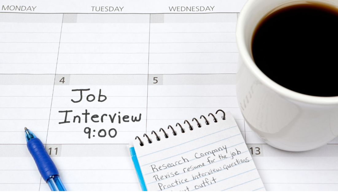 Calendar showing a scheduled job interview beside preparation notes, a pen, and a cup of coffee.