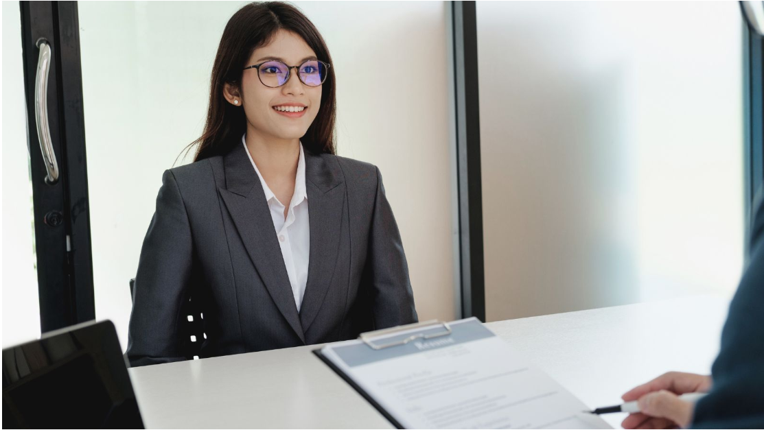 Professionally dressed candidate speaking with an employer during a formal job interview.