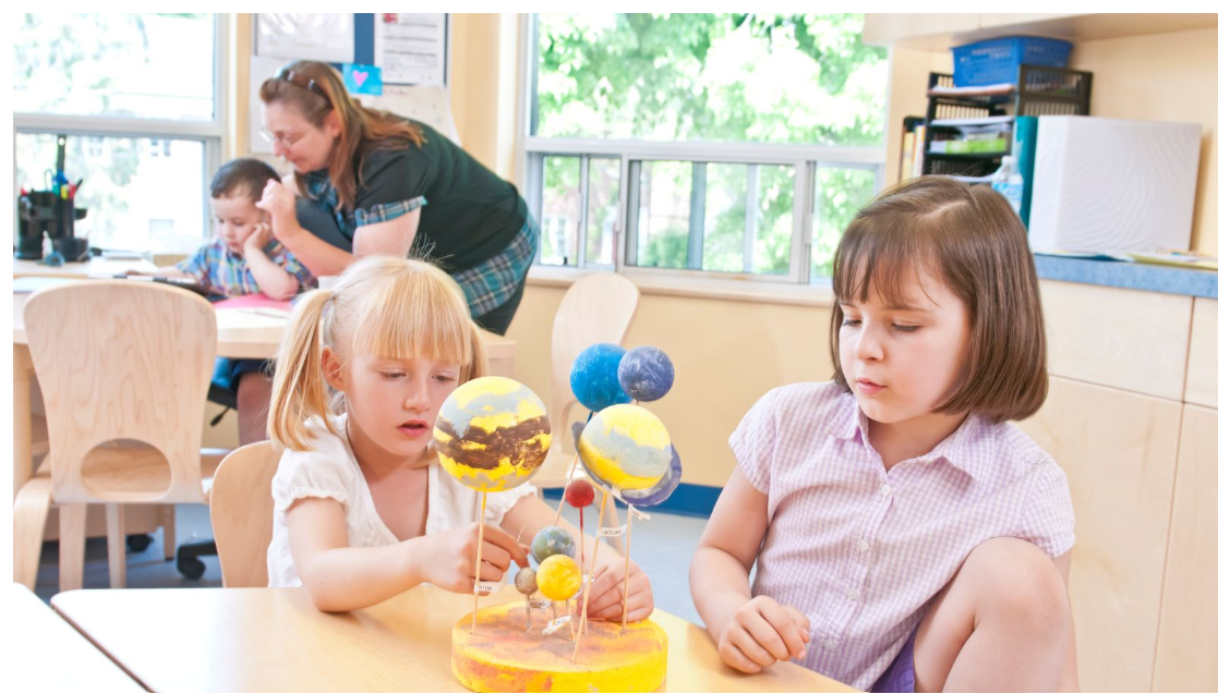 Children exploring a model of the solar system with support from an early childhood educator.