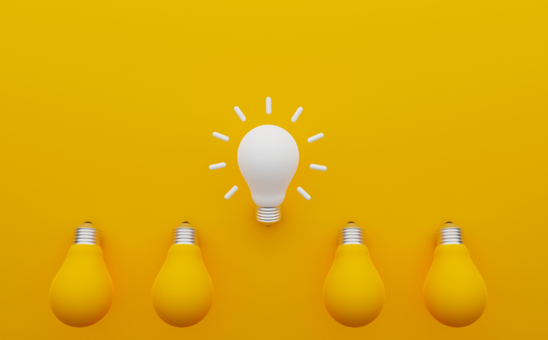 White light bulb glowing above four unlit bulbs on a yellow background, representing innovation, skills development, and new career opportunities.